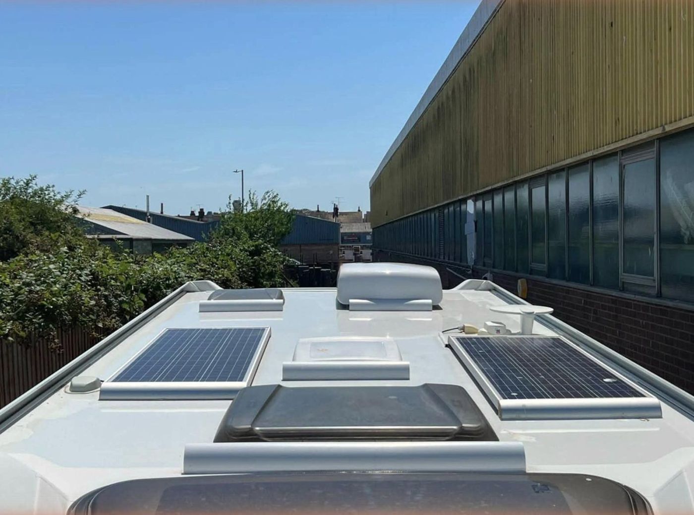 A motorhome roof with two solar panels fitted, under a blue sky